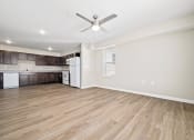 Thumbnail 26 of 35 - an empty living room with a ceiling fan and a kitchen