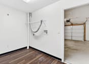 Thumbnail 40 of 49 - A room with a wooden floor and a white wall with a pipe running along it.