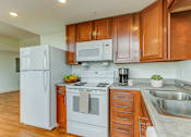 Thumbnail 29 of 30 - A kitchen with wooden cabinets and white appliances.