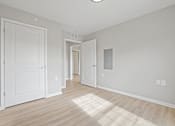 Thumbnail 18 of 78 - an empty living room with white doors and wood flooring