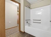 Thumbnail 50 of 66 - A white bathtub with a shower head and grab bars is in a bathroom.