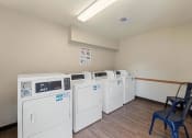 Thumbnail 29 of 37 - a row of washers and dryers in a room with a chair