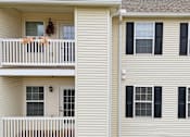 Thumbnail 54 of 66 - A white house with a balcony and black shutters.