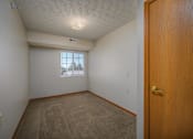 Thumbnail 13 of 33 - A room with a brown carpet and a wooden door.