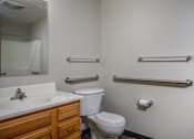 Thumbnail 23 of 33 - A bathroom with a toilet, sink, and grab bars.