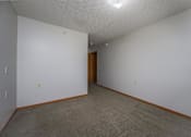 Thumbnail 24 of 33 - A room with a carpeted floor and a brown door.
