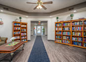 Thumbnail 31 of 33 - A room with a ceiling fan and bookshelves filled with books.