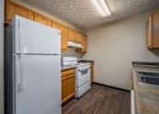 Thumbnail 16 of 33 - A white refrigerator stands in a kitchen with wooden cabinets and a white dishwasher.