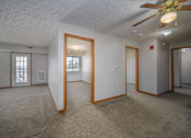 Thumbnail 14 of 33 - A spacious room with a ceiling fan and carpeted floor.