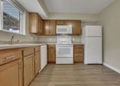 Thumbnail 4 of 9 - A kitchen with wooden cabinets and white appliances.