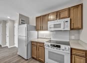 Thumbnail 9 of 18 - A kitchen with white appliances and wooden cabinets.