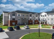 Thumbnail 7 of 22 - an exterior view of an apartment building with cars parked in a parking lot