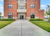 Thumbnail 2 of 25 - a large brick building with a concrete walkway in front of it
