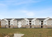 Thumbnail 21 of 56 - an apartment building with a field in front of it