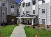 Thumbnail 4 of 22 - a pathway leading to an apartment building with a porch