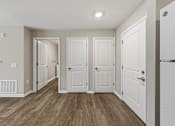 Thumbnail 18 of 53 - A hallway with white doors and wooden floors.