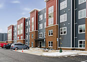 Thumbnail 37 of 53 - A row of apartment buildings with cars parked in front.