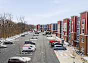 Thumbnail 49 of 53 - A parking lot with cars and apartment buildings on the side.