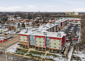 Thumbnail 39 of 53 - A large apartment complex with a parking lot in front.