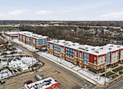 Thumbnail 40 of 53 - A large apartment complex is surrounded by a parking lot and a road.