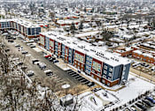 Thumbnail 34 of 53 - A large building complex with a parking lot in front.