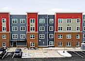 Thumbnail 45 of 53 - Apartment building with a parking lot in front.