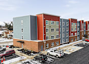 Thumbnail 47 of 53 - A row of multi-story buildings with cars parked in front.