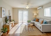 Thumbnail 29 of 30 - A living room with a grey couch, a coffee table, and a ceiling fan.