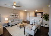 Thumbnail 11 of 11 - A living room with a grey sofa, a coffee table, and a ceiling fan.