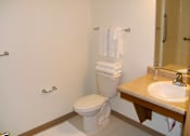 Thumbnail 18 of 20 - A white toilet is in a bathroom with a sink and towel rack.