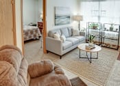Thumbnail 19 of 20 - A living room with a grey couch and a coffee table.