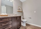 Thumbnail 50 of 52 - A bathroom with a toilet, sink, and wooden cabinets.