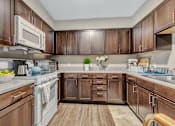 Thumbnail 51 of 52 - A kitchen with wooden cabinets and a white stove top oven.