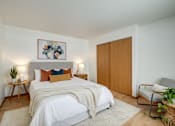 Thumbnail 7 of 9 - A bedroom with a bed, a chair, and a painting on the wall.