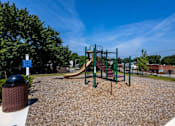 Thumbnail 25 of 38 - A playground with a slide, swings, and a trash can.