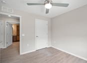 Thumbnail 13 of 19 - an empty living room with a ceiling fan and a door to a bedroom