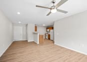 Thumbnail 9 of 19 - an empty living room with a ceiling fan and a kitchen