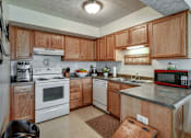 Thumbnail 14 of 17 - A kitchen with wooden cabinets and a white stove top oven.