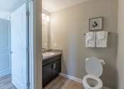 Thumbnail 54 of 55 - A bathroom with a toilet, sink, and a picture on the wall.