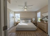 Thumbnail 53 of 55 - A bedroom with a large bed, a ceiling fan, and a window with a view of the outside.
