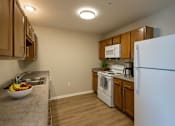 Thumbnail 22 of 24 - A kitchen with a white refrigerator, wooden cabinets, and a sink.