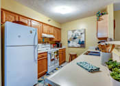 Thumbnail 36 of 36 - A kitchen with a white fridge and wooden cabinets.