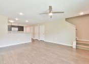 Thumbnail 11 of 29 - a living room with a ceiling fan and a kitchen in the background