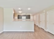 Thumbnail 23 of 29 - a kitchen and living room with white walls and wood floors