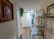 Thumbnail 10 of 27 - a hallway with a shelf of glasses and a door to a room with a staircase