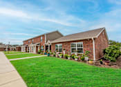 Thumbnail 17 of 27 - a row of houses on a street with a green lawn and potted plants