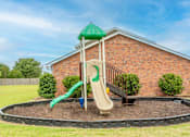 Thumbnail 18 of 27 - a playground with a slide in front of a brick building