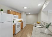 Thumbnail 37 of 39 - A kitchen with a white refrigerator, wooden cabinets, and a white countertop.