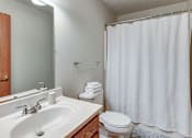 Thumbnail 19 of 20 - A white bathroom with a toilet, sink, and shower curtain.