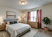 Thumbnail 17 of 20 - A bedroom with a large bed, two lamps, and a potted plant.